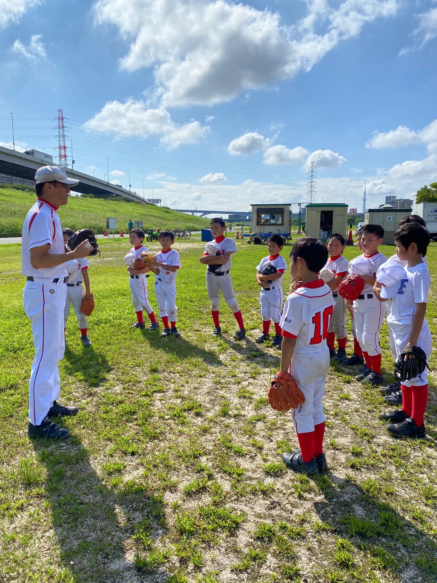 梅雨明けのAM、夏空の下で練習への心構えを聞いている（はず）の子供たち